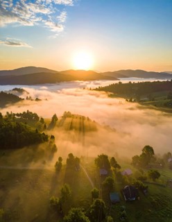 Sunrise over a fog covered village in a rural landscape, golden morning light, serene autumn