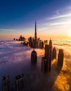 City scape emerging from a dense enveloping fog in sunrise and skyscrapers piercing the haze, big