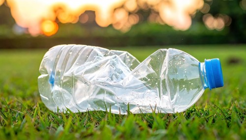 Crushed plastic water bottle waste in a wild landscape, symbol for nature protection, waste