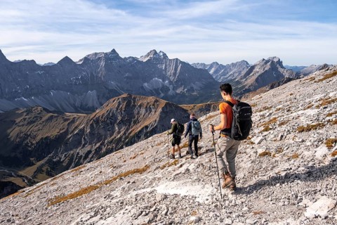 Hikers on the summit ridge of the Gamsjoch, behind rock faces of the Laliderer Spitze, eastern