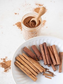 Cinnamon sticks displaying ceylon and cassia varieties with a jar of ground cinnamon powder