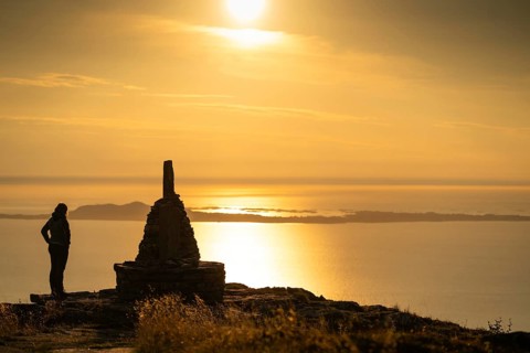 Woman standing next to cairn and looking at the sea, Rørsethornet stone staircase, with 3292 steps