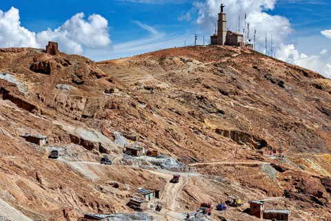 Statue on a hill with some huts and a dry, dusty mountain behind, The silver mines of Potosi
