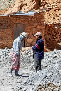 Two men in work clothes talk in a dusty mining landscape, The miners of the Cerro Rico silver