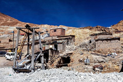 Weathered stone houses and huts on a mountainside with a clear sky, The silver mines of Potosi