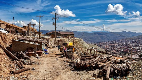 Rustic village scene with huts and mountains in the background under a cloudy sky, The silver mines