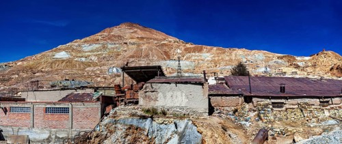 Abandoned buildings on a mountainside with a rocky landscape and a clear blue sky, The silver mines