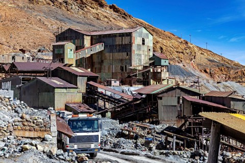 Old industrial complex with a lorry in a mountainous environment under a clear blue sky, The silver