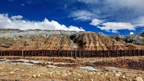Barren mountain landscape with steep slopes under a blue sky with clouds, spoil heap of the silver