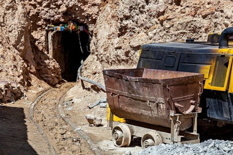 A mine car and a machine near the entrance of a rocky mine, The silver mines of the Cerro Rico
