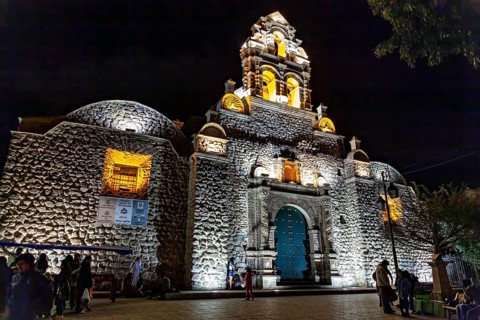 Illuminated church at night with impressive architecture and blue Tor tor, surrounded by evening