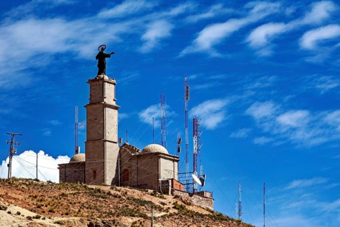 Tower with statue and antennae on a hill under a clear blue sky, The church on the Cerro Rico