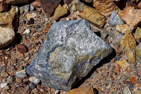A large, grey rock on a soil of pebbles and earth, the silver ore from the Cerro Rico silver