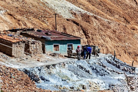 Miners in front of a house with wheelbarrows in a rocky landscape with railings, The silver mines