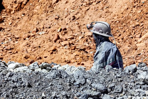 A miner gazes into the distance, surrounded by rocks and dusty terrain, The miners of the Cerro