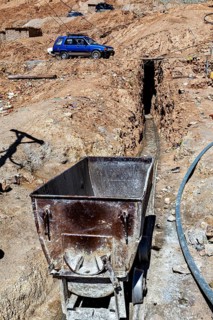 An old mining wagon stands next to a trench in an arid landscape, The silver mines of Potosi