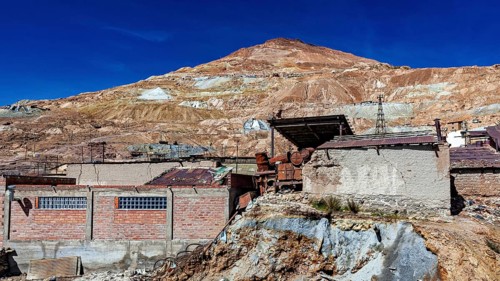 Abandoned mine buildings in front of a barren hill and clear sky, The silver mines of Potosi