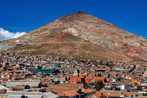 City at the foot of a large, barren mountain under a clear sky, the Cerro Rico silver mountain in