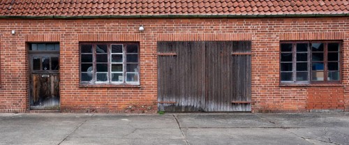 View of the entrance area of an older residential building with a red brick workshop, Uenzen,
