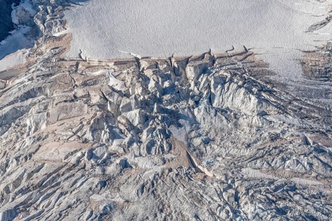 Intricate patterns of ice and rock are showcased in this stunning glacial landscape, revealing the