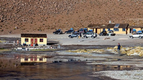 Huts and vehicles in a mountainous landscape with people, The thermal springs of Polques in Bolivia