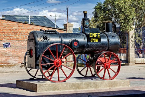 Old steam engine with red wheels stands on a pedestal in the open air in Bolivia, Old historic