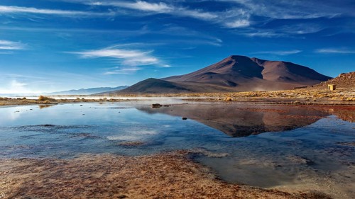 Peaceful mountain landscape with a clear lake and clouds in the sky creating a tranquil atmosphere,