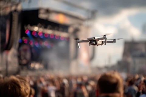 Ein Fernpilot steuert sein Quadrocopter, Drohne illegal über ein Open-Air Musik Konzert mit vielen