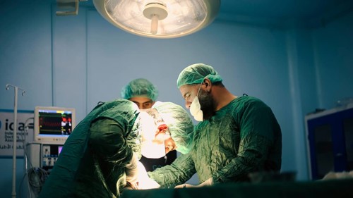 Several doctors performing a complex surgical operation inside an operating room for a displaced
