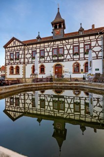 Historic half-timbered building reflected in the calm water basin against a blue sky, Historic