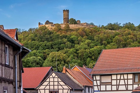 A quiet village scene with half-timbered houses and a castle on a hill, the ruins of Mühlburg