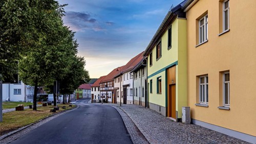 Row of houses in a quiet street with colourful facades and evening sky, the village of Mühlburg in
