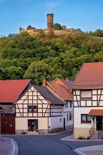 A village with half-timbered houses and a hill with a castle in the background, the ruin Mühlburg
