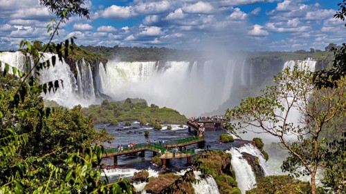 Dense vegetation surrounds a platform from which visitors can view the waterfalls, The Iguazu Falls