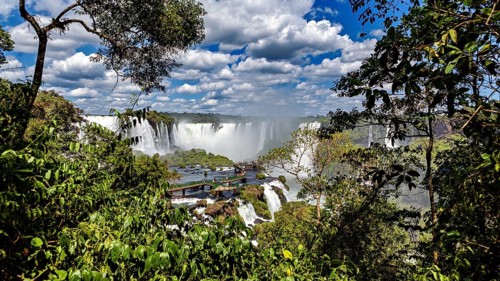 Lush green surroundings, waterfalls in the background, viewpoint with visitors, The Iguazu Falls