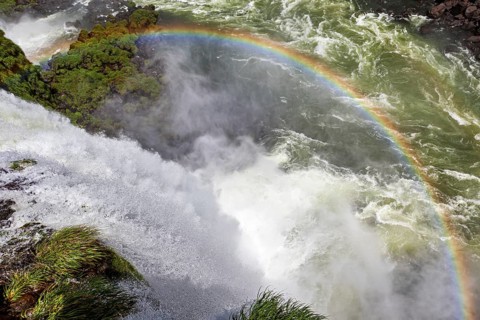 A glowing rainbow appears over a thundering waterfall, The Iguazu Falls between Argentina and