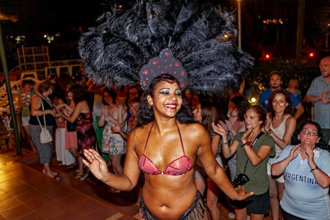 Dancer with feather headdress dances in front of an applauding audience, Samba dancers to entertain