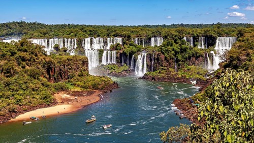 River course to the waterfalls, lined with forest and small boats, The waterfalls of Iguazu between