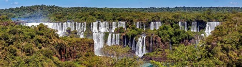 Sweeping view of the waterfalls with flowing river and green forest, The Iguazu Falls between