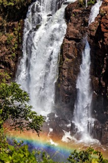 Bright rainbow in front of a powerful waterfall and green vegetation, The Iguazu Falls between