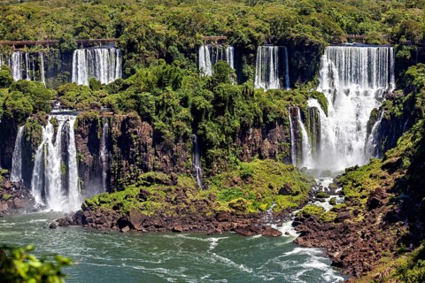 Various waterfalls flow over rocky cliffs, embedded in a lush green landscape, The Iguazu Falls
