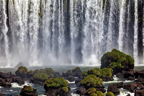A majestic waterfall cascades over rocks covered in moss, The Iguazu Falls between Argentina and