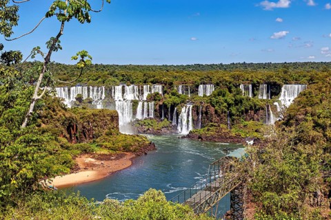 Panorama of the waterfalls with walkway along the river and dense deciduous forest, The Iguazu