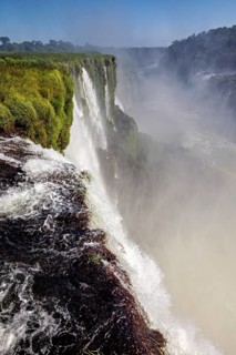 Majestic view of the waterfall, surrounded by green grass and rising mist, The Iguazu Falls between