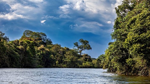 Wide river under a veiled sky, surrounded by dense forests, The Iguazu River between Argentina and