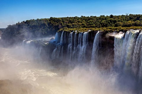 Row of waterfalls creates mist over green cliffs and conveys a peaceful atmosphere, The Iguazu
