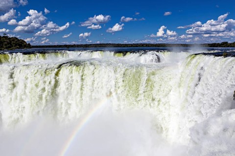 Spectacular waterfall with rainbow and spray under a cloudy sky, The Iguazu Falls between Argentina
