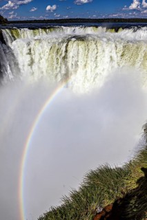 Dramatic waterfall with rainbow and spray under a blue sky, The Iguazu Falls between Argentina and