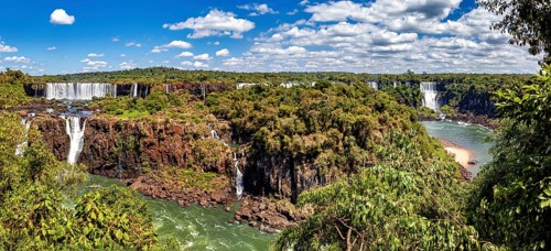 Sweeping views of waterfalls and river, surrounded by lush vegetation under a cloudy sky, The