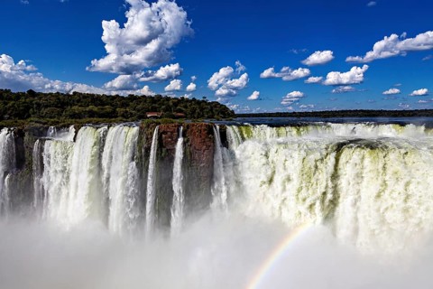 Majestic waterfall with rainbow under a clear sky and scattered clouds, The Iguazu Falls between